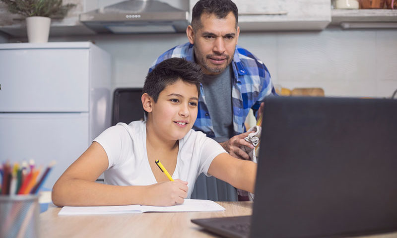 Father and son working together on a laptop at home